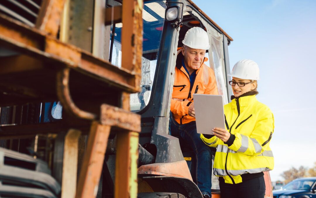 Worker in forklift and forewomen looking into task list on a tablet computer